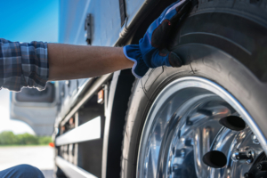 Caucasian Professional Trucker Examining Semi Truck Tire Close Up Photo